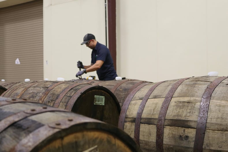 A worker inspects bourbon barrels